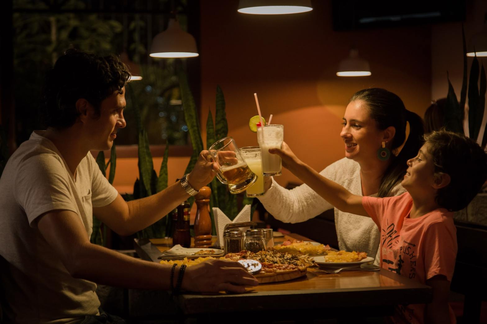 A family of three having a meal and cheering their glasses