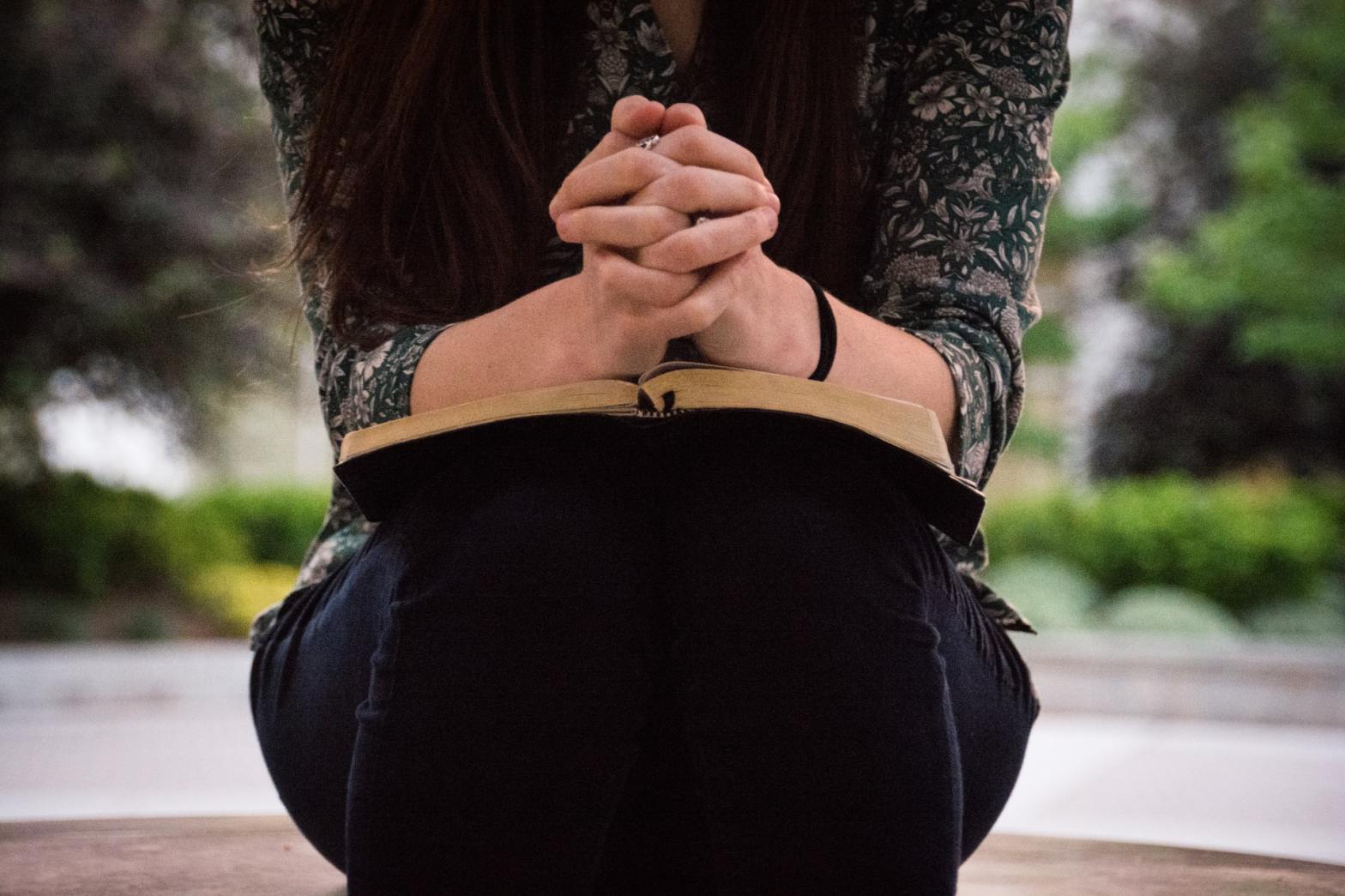 Woman praying with hands resting on the Bible