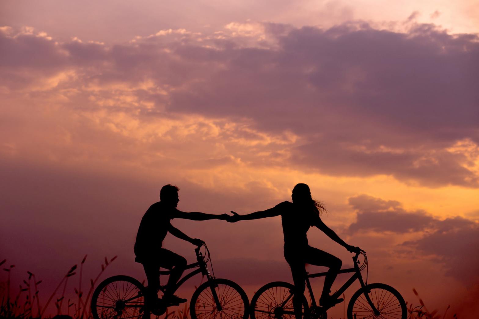 Silhouette of two people biking