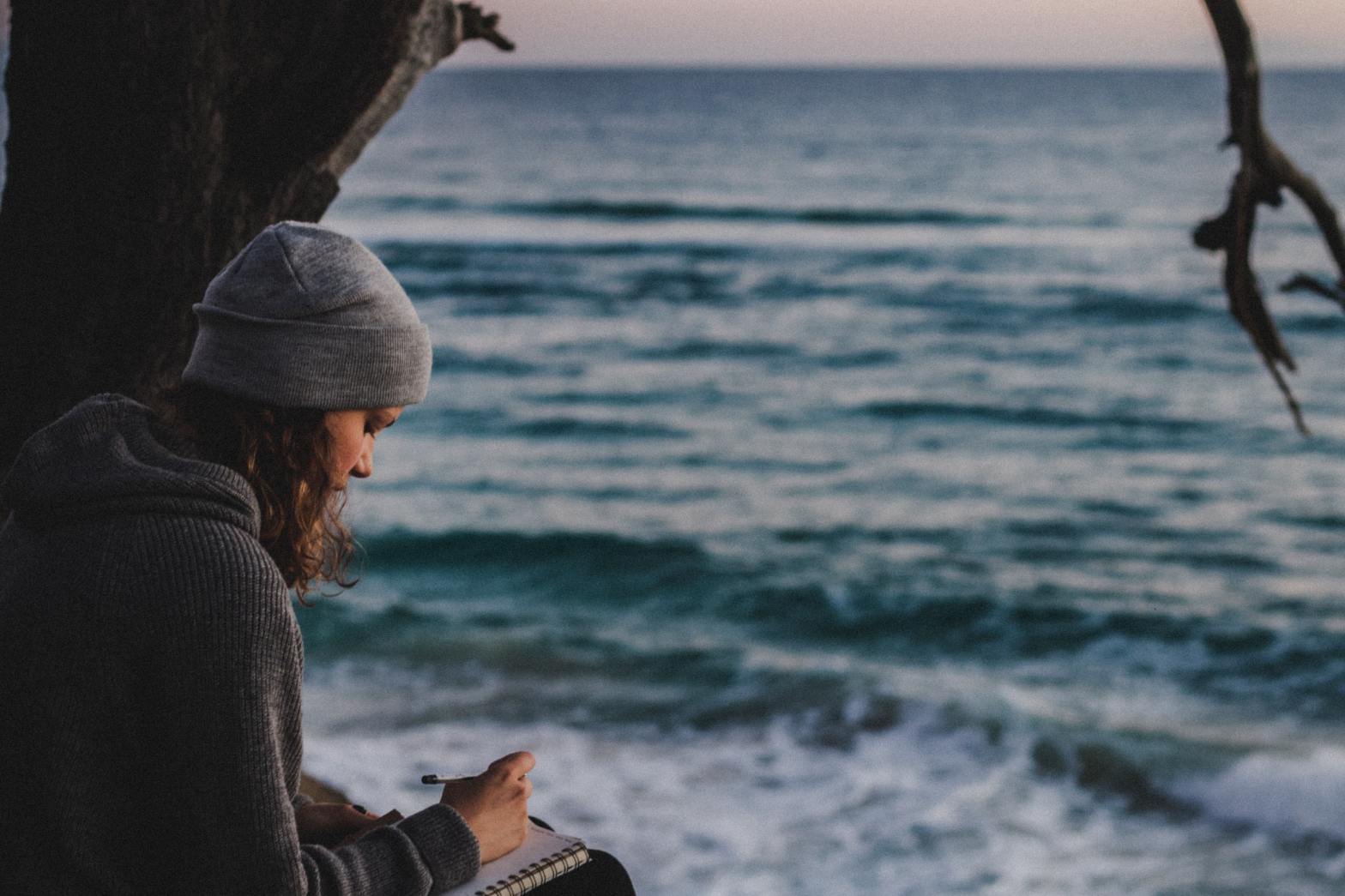 A girl writing by the shore