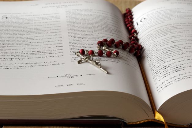 There is a rosary on top of an open Bible.