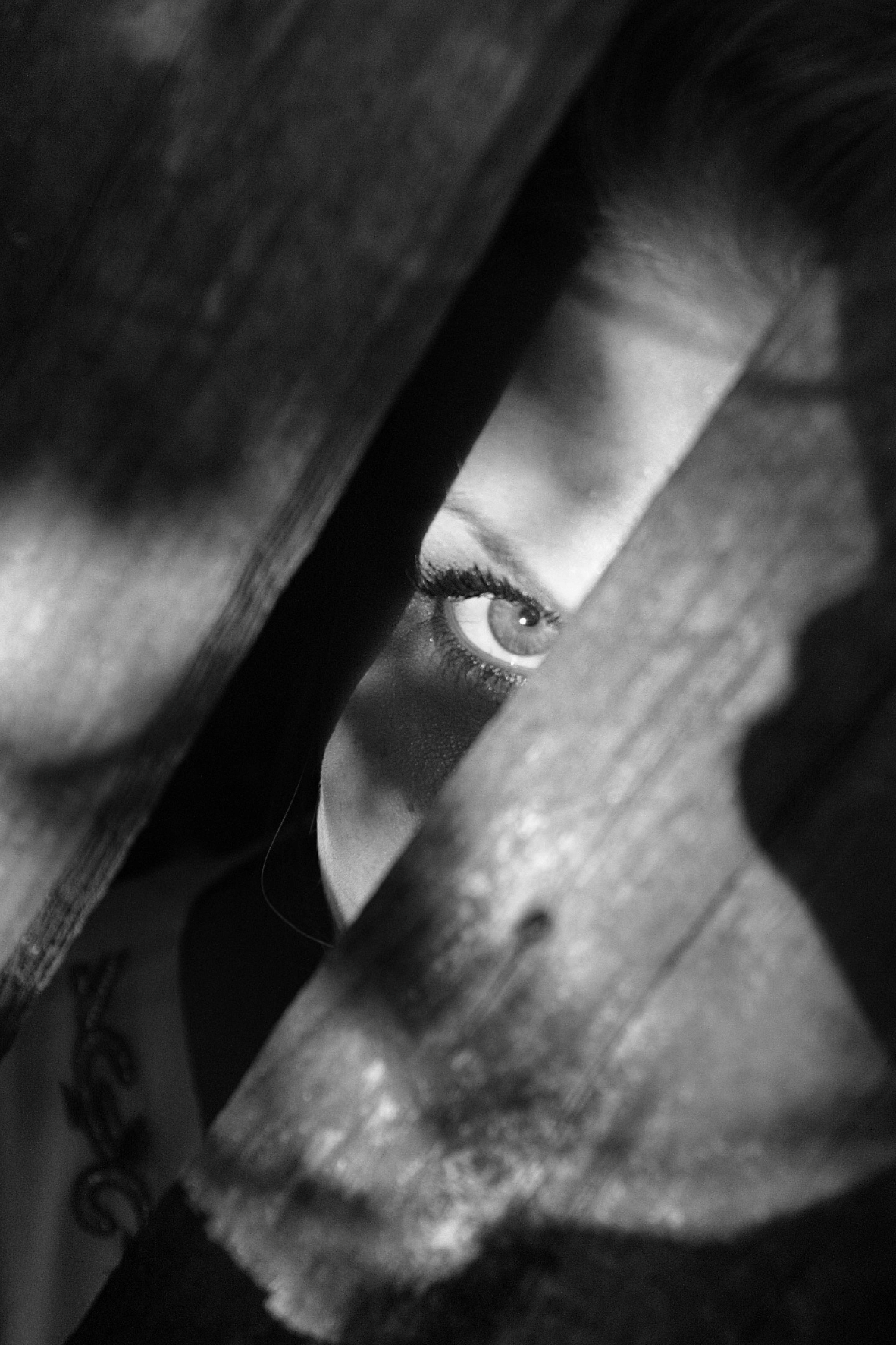A woman is peeking out from the planks.