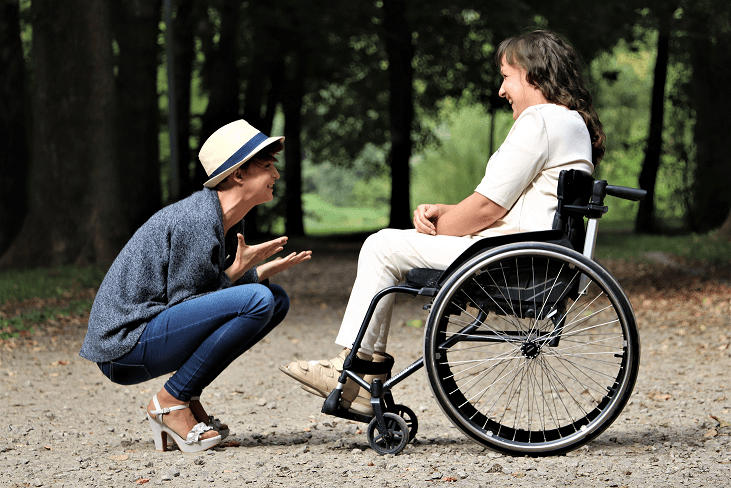 Woman on wheelchair while another person is talking in front of her.